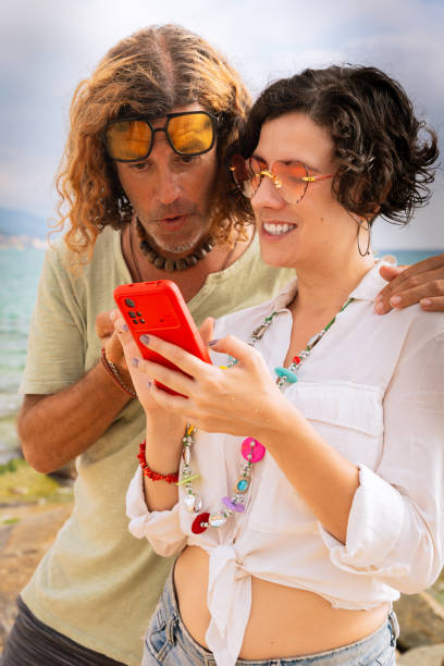 istock Vertical portrait smiling couple on the beach browsing smartphone apps. 2160218037