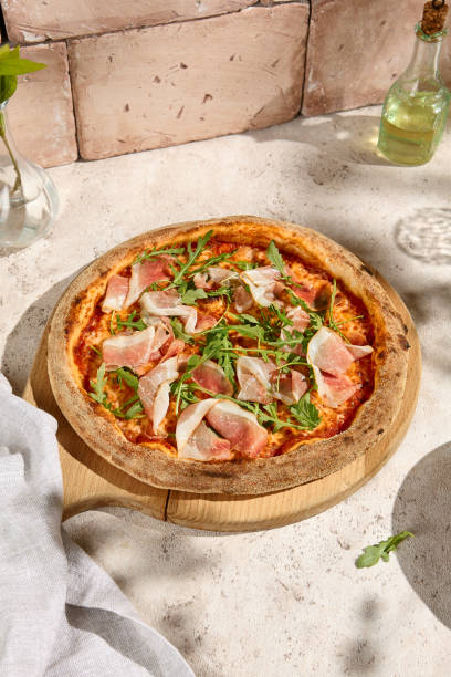 istock Delicious Parma Ham and Arugula Pizza in Sunlit Summer Setting 2160218262