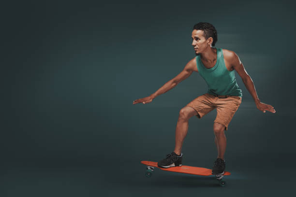 Studio shot of a young man riding a skateboard isolated on dark background.