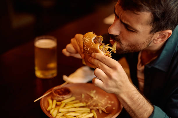 istock Young man enjoying in eating hamburger in a pub. 2160226545