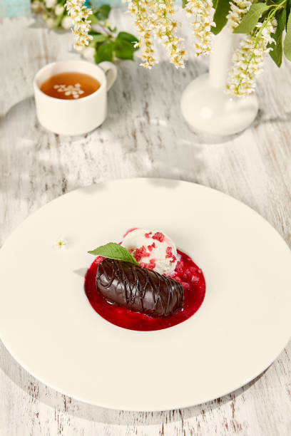 istock Chocolate Potato Pastry with Ice Cream and Raspberry Sauce in Sunlit Setting on Wooden Table 2160228159