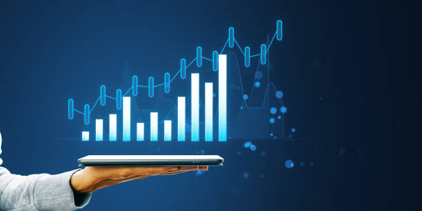 istock A person's hand holding a tablet displaying a holographic growth chart on a dark blue background, symbolizing business analytics 2160228500