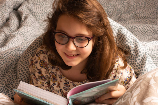 istock girl smiling while reading in bed 2160228760