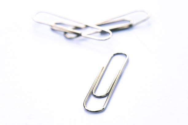 Rusty old black metal paper clips isolated on white
