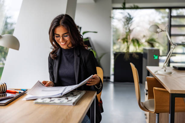 istock Smiling young female student reading in office 2160234731