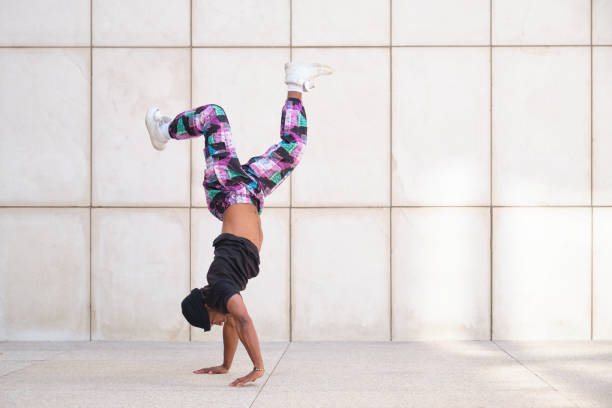 Young man dancing breakdance handstand against white wall