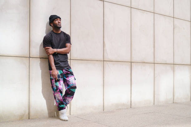 istock Young urban man leaning against wall holding mobile phone 2160240562