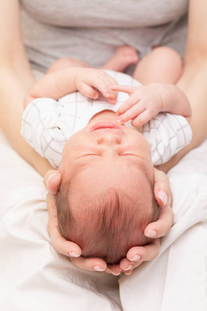 istock Mother Cradling Crying Newborn in Her Arms 2160243294