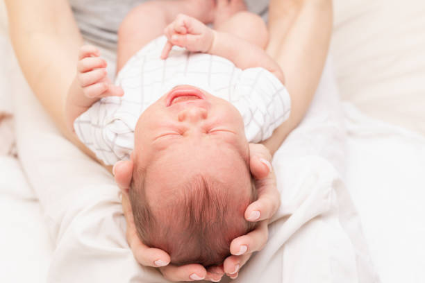 istock Mother Cradling Crying Newborn in Her Arms 2160243328