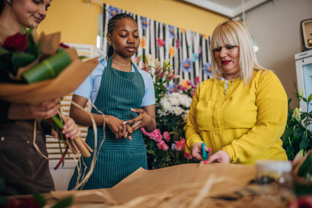 istock Three florists focused on flower arrangement and wrapping paper. 2160246190