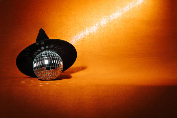 istock A witch hat and a disco ball on an orange Halloween background 2160251393