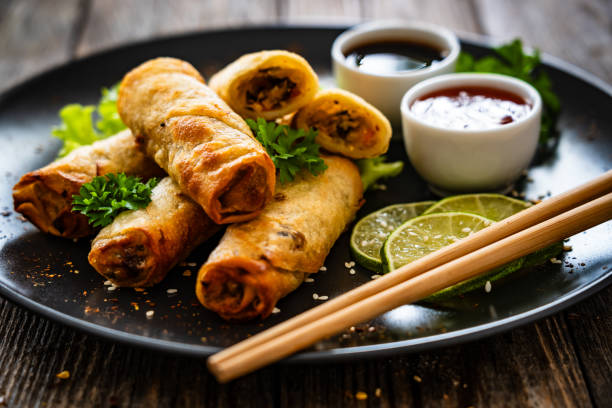 istock Spring rolls filled with meat and vegetables served with soy sauce on wooden table 2160251754