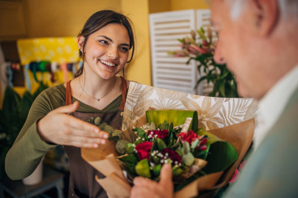 istock Young florist interacting with elderly customer cheerfully 2160252400