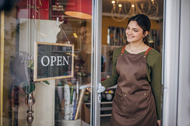 istock Young florist switching door sign to open cheerfully 2160252880