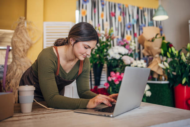 istock Florist typing on laptop in flower shop workspace. 2160261279