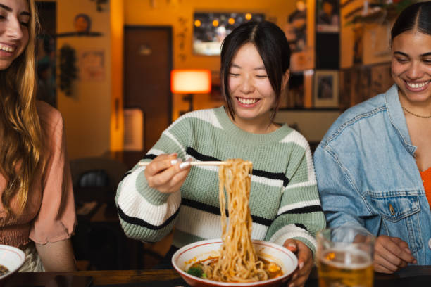 istock young woman using chopsticks while enjoying a bowl of delicious ramen 2160262842