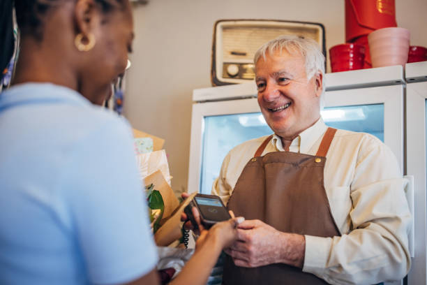 istock Customer handing payment device to elderly florist. 2160265870