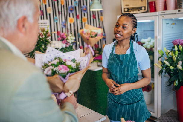 istock Elderly man buying flowers from young florist trainee 2160266904