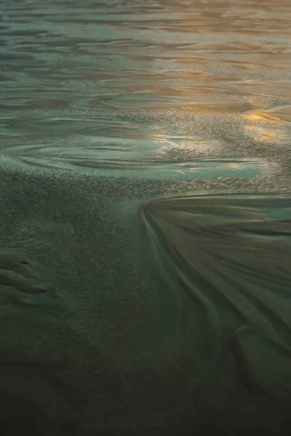istock Close-up of intricate sand patterns on a beach with a soft glow from the setting sun 2160270385