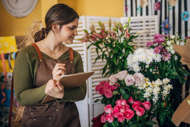 istock Florist Writing on Clipboard Surrounded by Flowers 2160271862