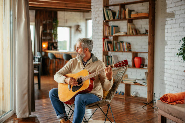 istock Senior man playing guitar  in living room 2160272758