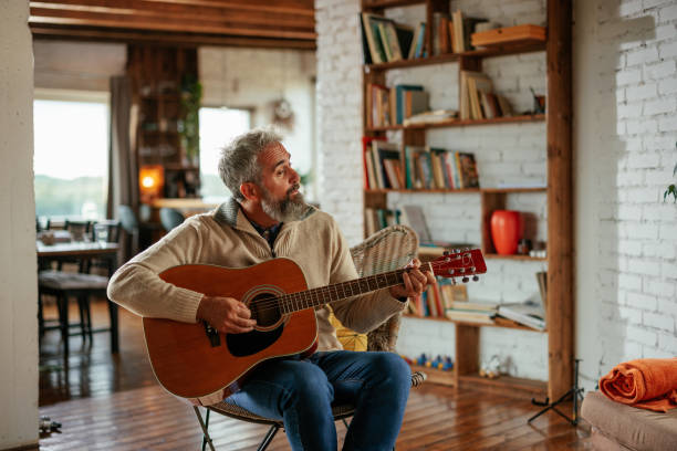 istock Man playing an acoustic guitar at home 2160272764