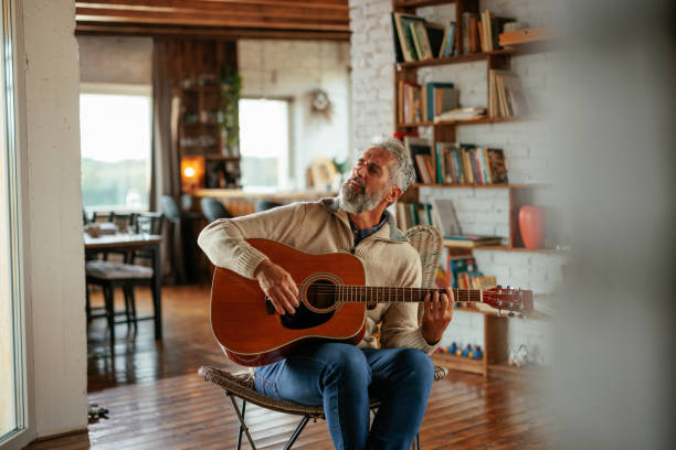 istock Man enjoying playing an acoustic guitar at home 2160272791