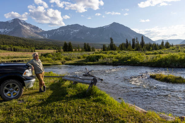istock Senior man leans against vehicle in meadow 2160275123