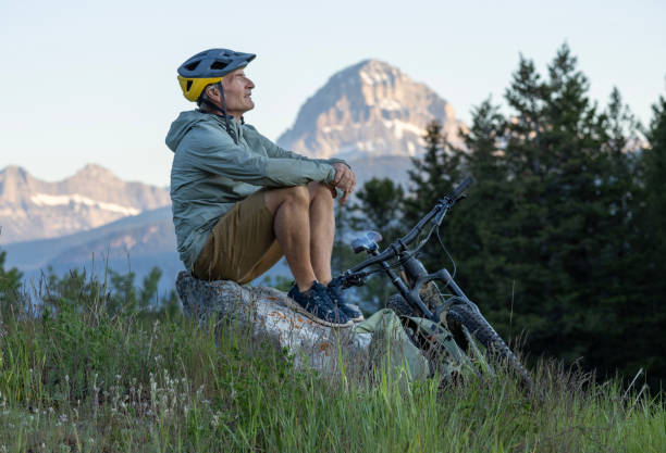 istock Mountain biker looks off, snowcapped mountain distant 2160275412