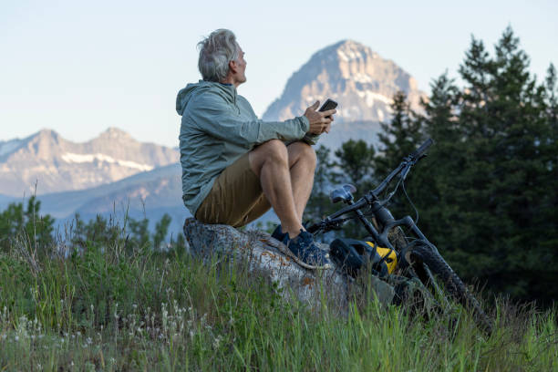 istock Mountain biker uses mobile phone in meadow 2160275598
