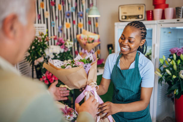 istock Smiling florist handing bouquet to a customer, joyful. 2160278847