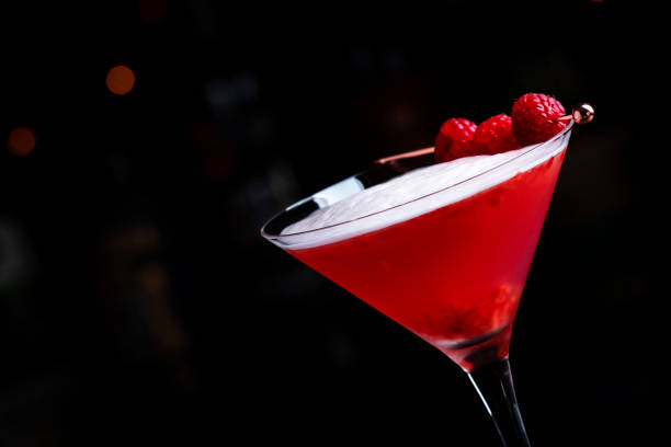 istock Summer red  cocktail with gin, raspberry syrup, lime juice, quail egg white and ice in glass. Black bar counter background 2160293317