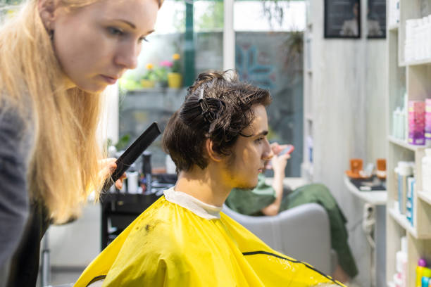 istock Hair stylist combing client's hair at salon 2160299708