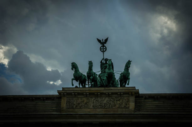 Close-up of the Quadriga sculpture atop the Brandenburg Gate in Berlin, Germany, featuring a four-horse chariot and the goddess of victory against a cloudy sky