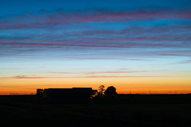 Beautiful purple clouds and twilight colors over a silhouetted farm in the Dutch countryside.