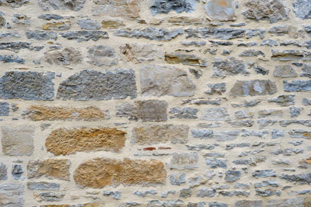 Background of a natural stone or sandstone masonry wall texture with cement in South France. Detailed stone texture image in beige, brown, grey and blue