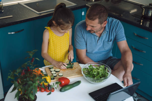 istock Father and Daughter Cutting Vegetables at the Table 2160305277