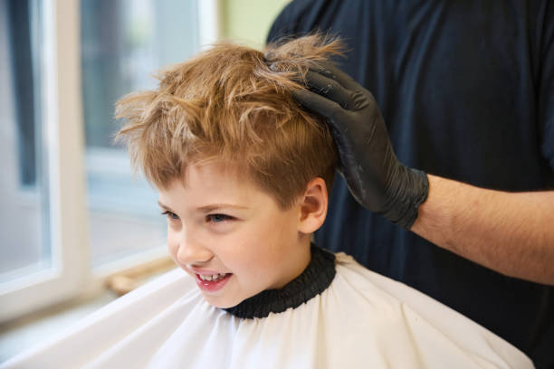 istock High-qualified barber modeling little boy hairstyle using hair molding cream 2160317096