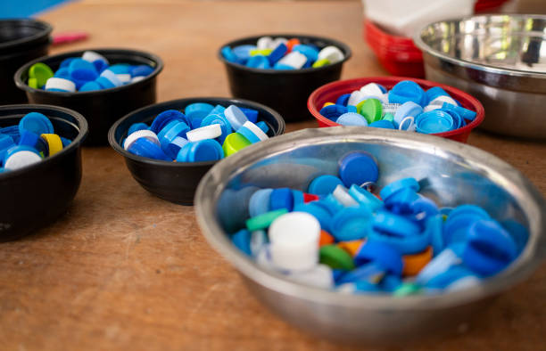 Close-up of a collection of multi colored bottle caps in bowls on a floor waiting to be recycled into something new