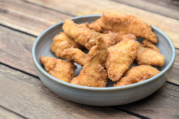 istock Deep-fried chicken pieces with golden and crispy panko breading in a gray ceramic bowl on a rustic wooden table ready to eat, copy space 2160325038