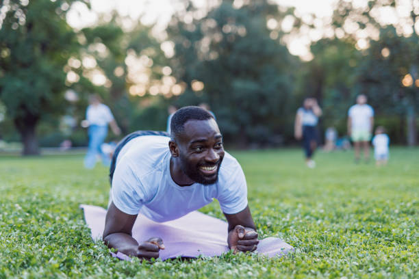 istock Cheerful man maintaining plank pose in the park. 2160325624