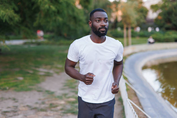 istock Focused man jogs along pond path in casual attire. 2160325655