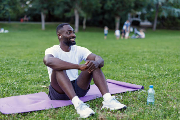 istock Man seated on mat in park, relaxed and smiling, enjoying nature 2160326564