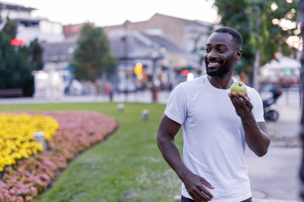 istock Man with apple walking in park amidst blooming flowers. 2160326691