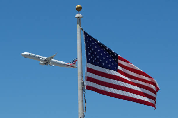 The American flag and an American Airlines jet in the distance shown moments after taking off from LAX, Los Angeles International Airport, in California.