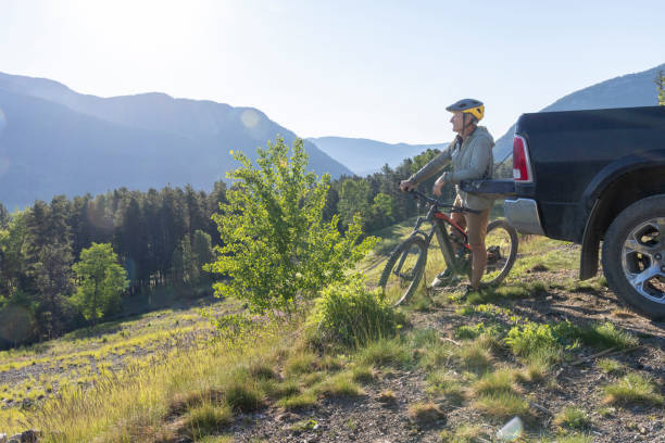 istock Mountain biker leans against vehicle in lush meadow 2160330853