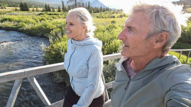 istock Senior couple walk across bridge over river 2160331216