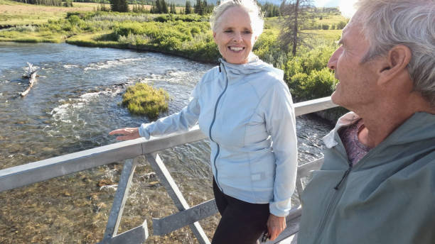 istock Senior couple walk across bridge over river 2160331218