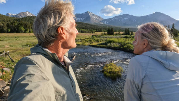 istock Senior couple walk across bridge over river 2160331312