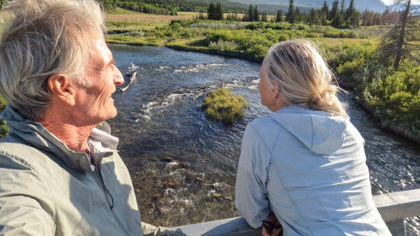 istock Senior couple walk across bridge over river 2160331313